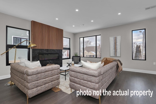 living room with a high end fireplace and dark hardwood / wood-style floors