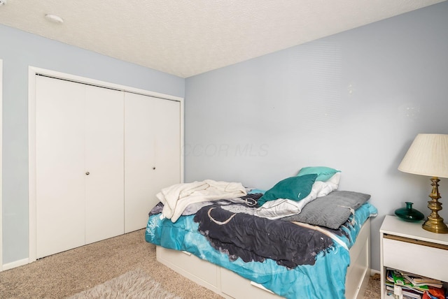 carpeted bedroom with a textured ceiling and a closet