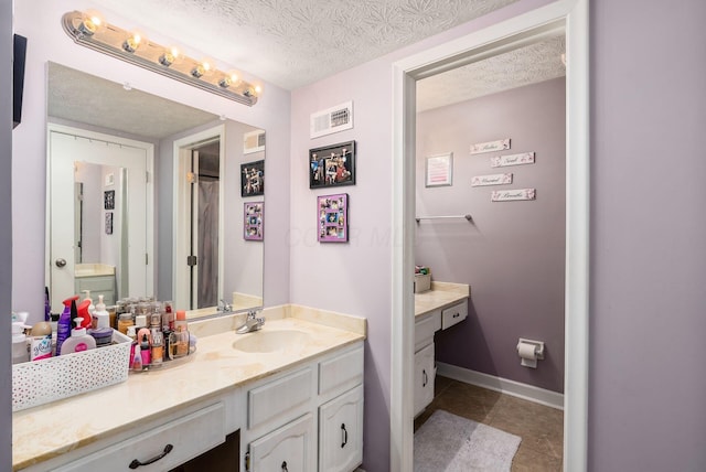 bathroom with tile patterned flooring, vanity, and a textured ceiling