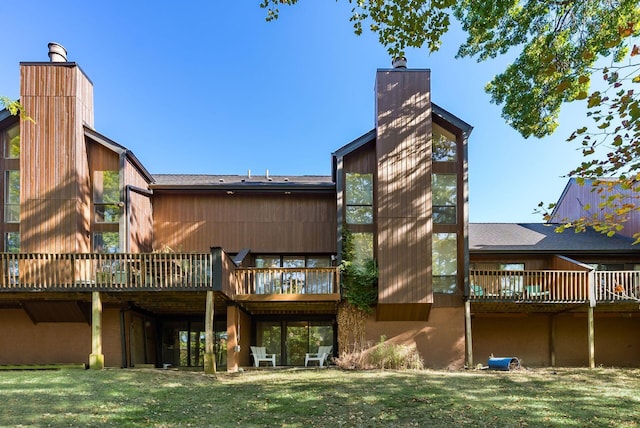 rear view of property featuring a deck and a lawn