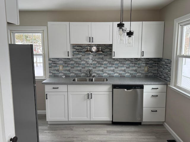 kitchen featuring stainless steel dishwasher, white cabinets, backsplash, and sink