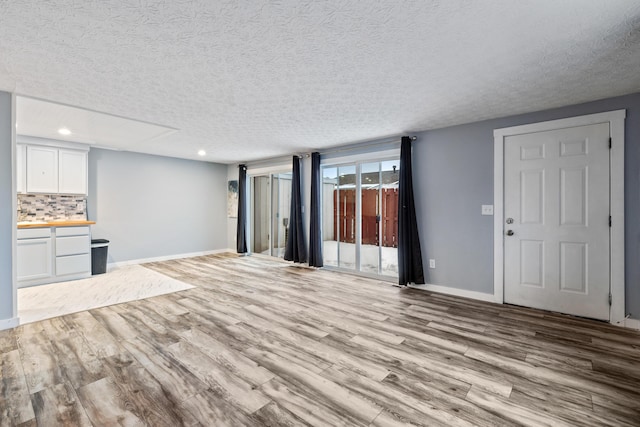 unfurnished living room featuring light hardwood / wood-style floors and a textured ceiling