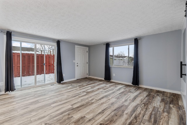 unfurnished room with a textured ceiling and light hardwood / wood-style flooring