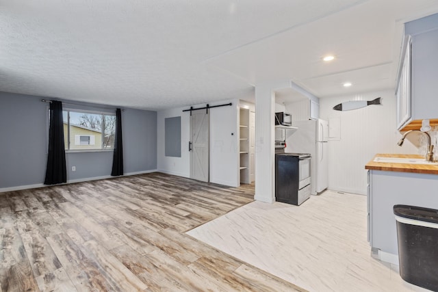 kitchen featuring sink, wooden counters, white cabinetry, stainless steel electric stove, and a barn door