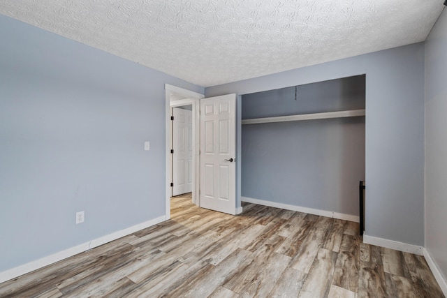 unfurnished bedroom with a closet, a textured ceiling, and light wood-type flooring