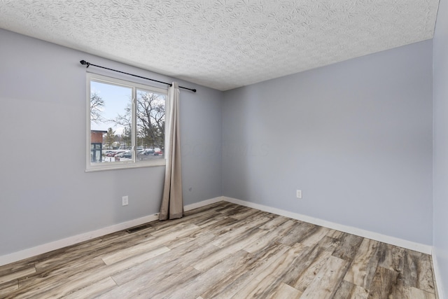 spare room featuring a textured ceiling and light wood-type flooring