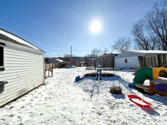 yard layered in snow with a trampoline