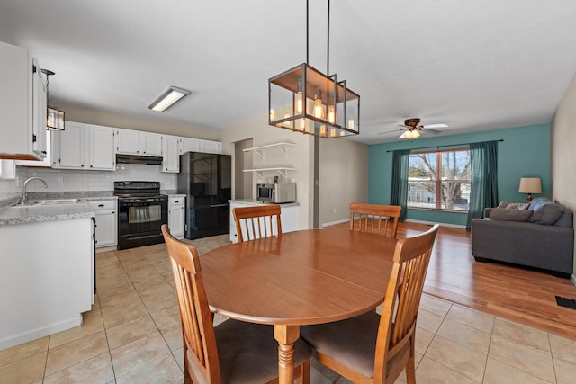 tiled dining room with sink and ceiling fan with notable chandelier