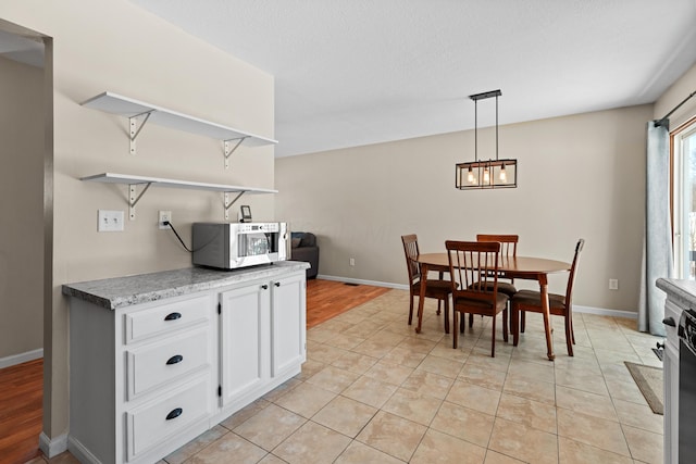 kitchen featuring light tile patterned floors, white cabinetry, and pendant lighting