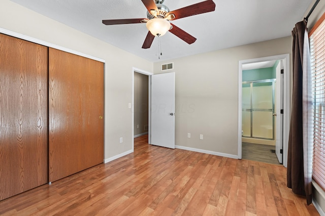 unfurnished bedroom featuring ensuite bathroom, ceiling fan, light hardwood / wood-style flooring, and a closet