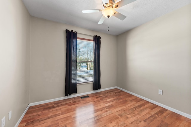 empty room with ceiling fan, hardwood / wood-style floors, and a textured ceiling