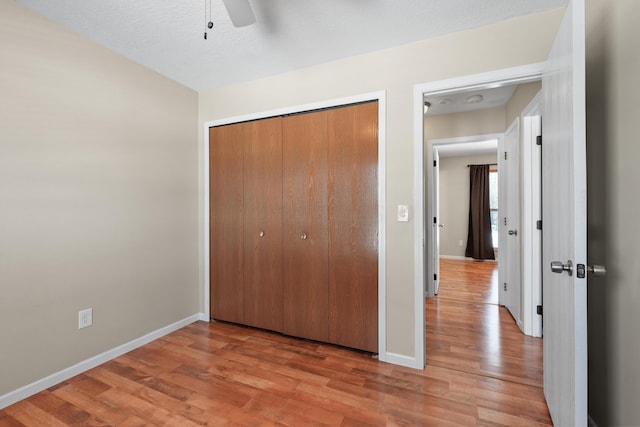 unfurnished bedroom with ceiling fan, light hardwood / wood-style floors, and a closet