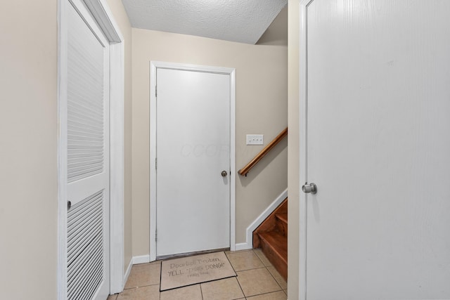 entryway featuring light tile patterned flooring and a textured ceiling