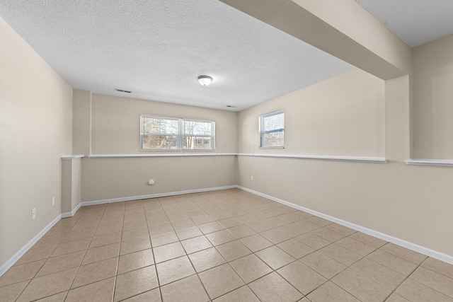 spare room featuring a textured ceiling and light tile patterned floors