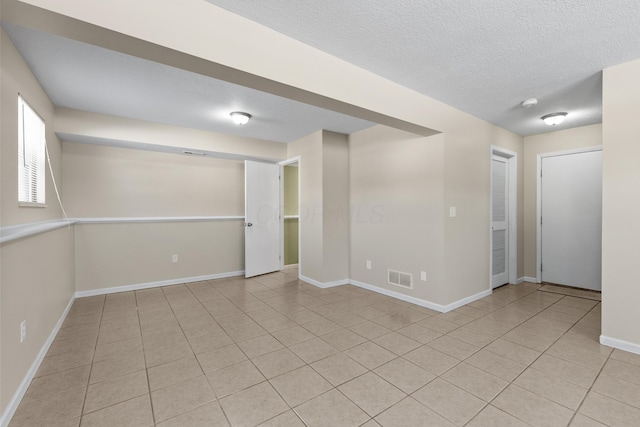 spare room featuring a textured ceiling and light tile patterned floors