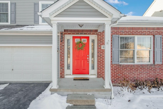 snow covered property entrance featuring a garage