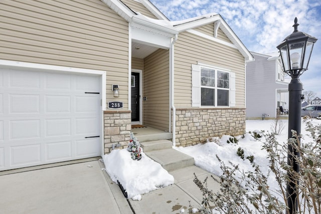 snow covered property entrance featuring a garage