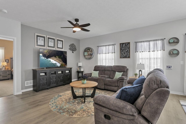 living room with ceiling fan, wood-type flooring, and a textured ceiling