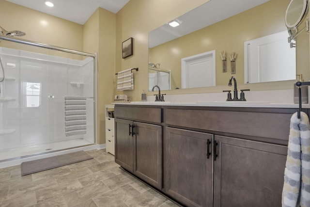 bathroom featuring a shower with door and vanity