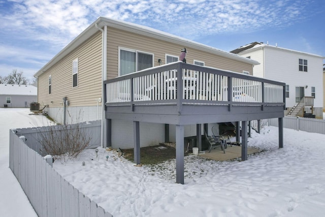 snow covered back of property featuring central AC unit and a deck