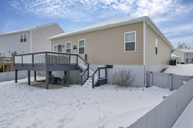 snow covered back of property with a deck