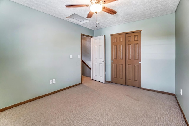 unfurnished bedroom with ceiling fan, light colored carpet, a closet, and a textured ceiling