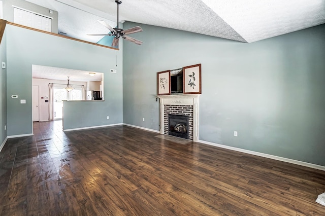 unfurnished living room with high vaulted ceiling, a tiled fireplace, ceiling fan, dark wood-type flooring, and a textured ceiling