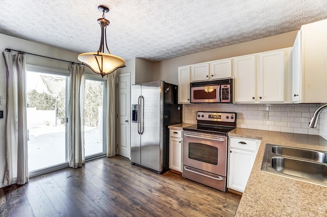 kitchen featuring white cabinetry, backsplash, dark hardwood / wood-style flooring, hanging light fixtures, and stainless steel appliances