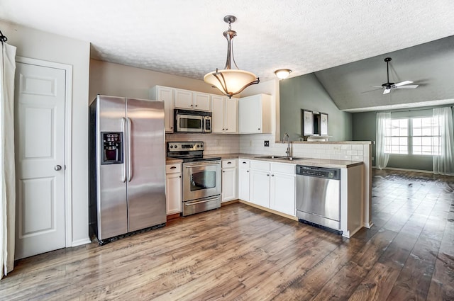 kitchen with sink, decorative light fixtures, appliances with stainless steel finishes, decorative backsplash, and white cabinets