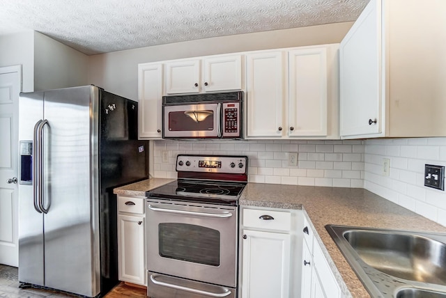 kitchen featuring tasteful backsplash, stainless steel appliances, a textured ceiling, and white cabinets