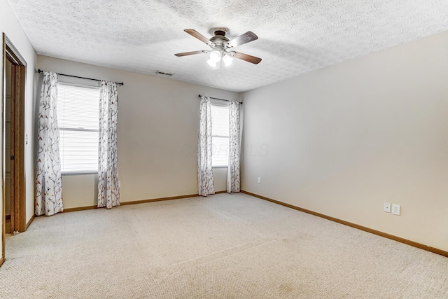 carpeted spare room featuring a textured ceiling and ceiling fan