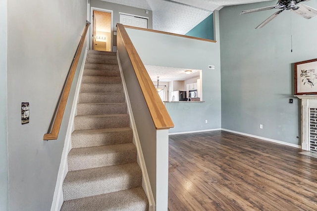 stairs with hardwood / wood-style flooring, ceiling fan, and high vaulted ceiling