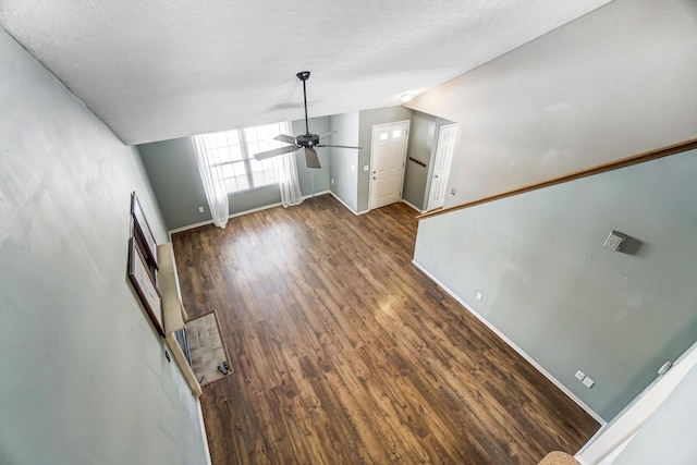 unfurnished living room with lofted ceiling, a textured ceiling, dark hardwood / wood-style floors, and ceiling fan