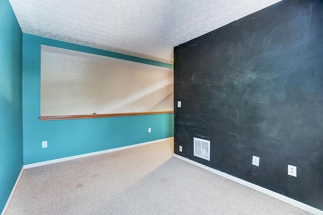 carpeted empty room featuring a textured ceiling