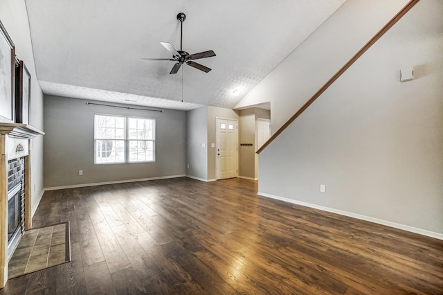 unfurnished living room with a tile fireplace, lofted ceiling, ceiling fan, and dark hardwood / wood-style flooring