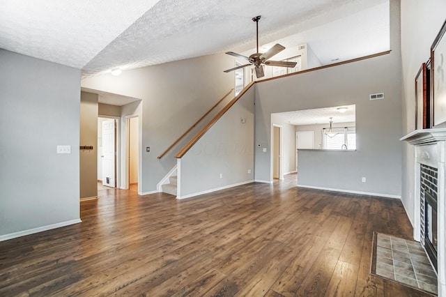 unfurnished living room featuring dark wood-type flooring, high vaulted ceiling, a textured ceiling, ceiling fan, and a tiled fireplace