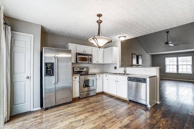 kitchen with sink, backsplash, stainless steel appliances, white cabinets, and decorative light fixtures