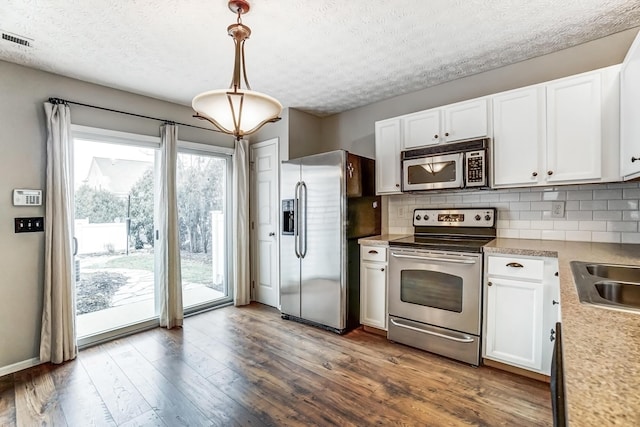 kitchen featuring pendant lighting, white cabinetry, stainless steel appliances, tasteful backsplash, and dark hardwood / wood-style flooring