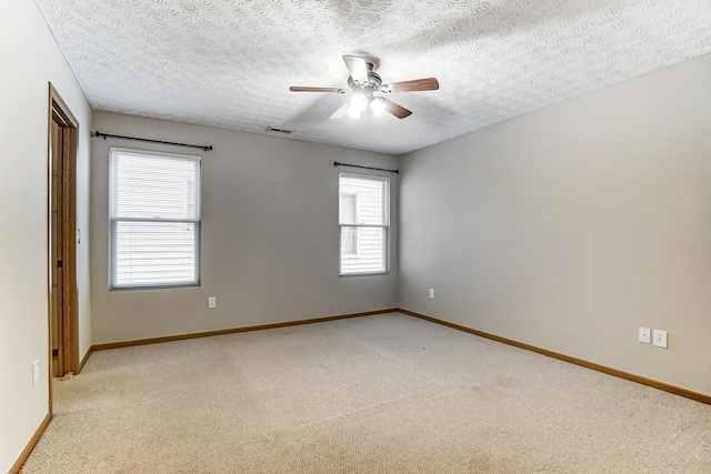 empty room featuring light carpet, a textured ceiling, and ceiling fan