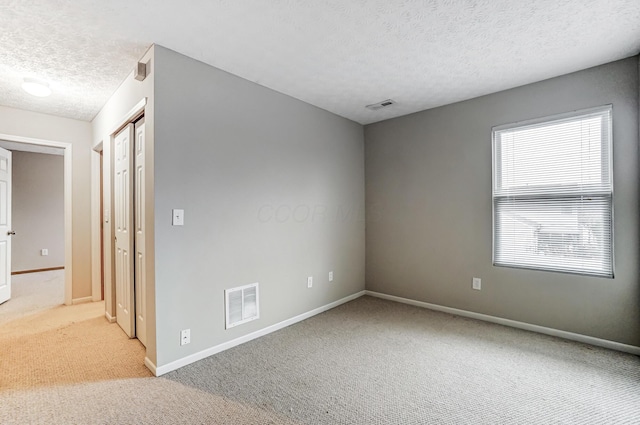 carpeted spare room with a textured ceiling