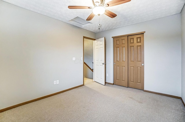 unfurnished bedroom featuring light carpet, ceiling fan, a closet, and a textured ceiling