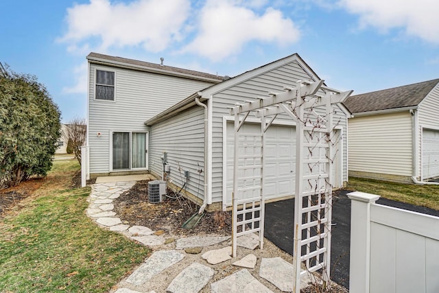 back of house with a pergola, a garage, a lawn, and central air condition unit