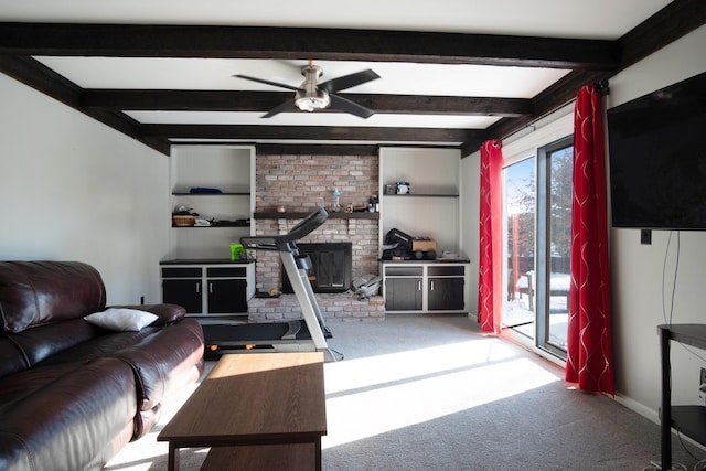 living room with a wood stove, built in shelves, carpet floors, ceiling fan, and beamed ceiling