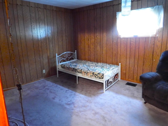 carpeted bedroom featuring wooden walls