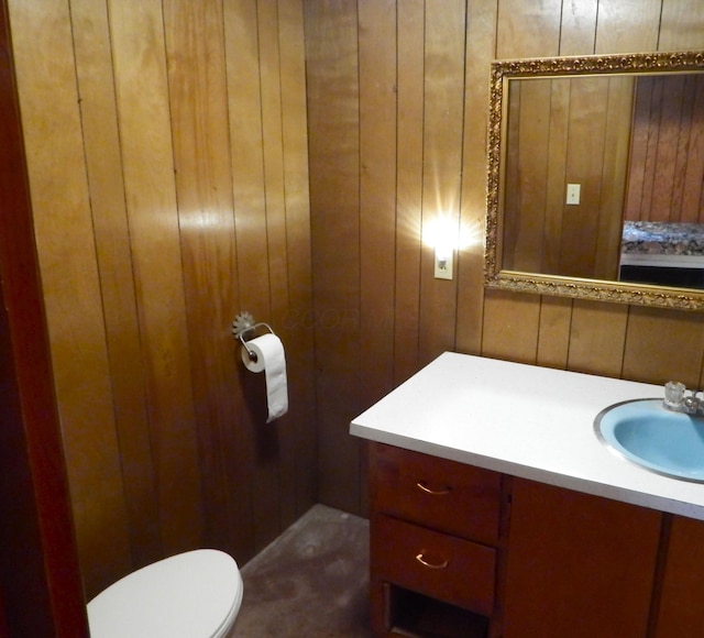 bathroom with toilet, vanity, and wooden walls