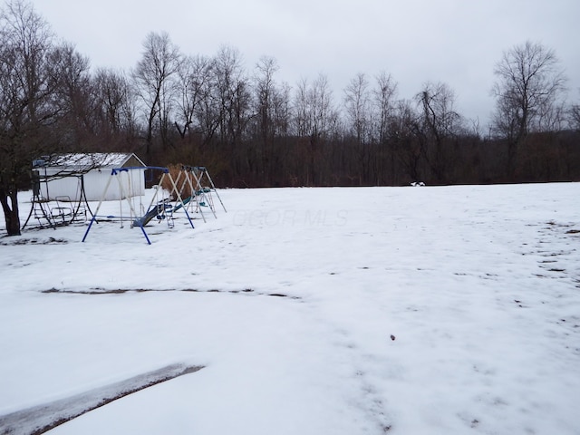 yard covered in snow featuring a playground