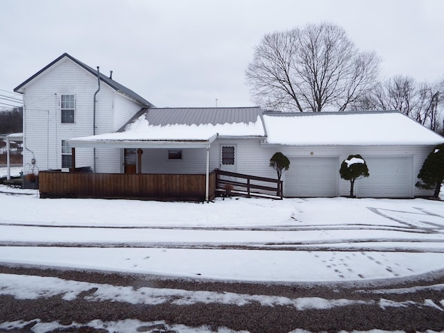 snow covered property featuring a porch and a garage