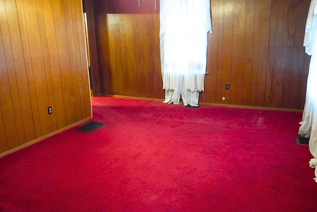 unfurnished room featuring carpet floors and wooden walls