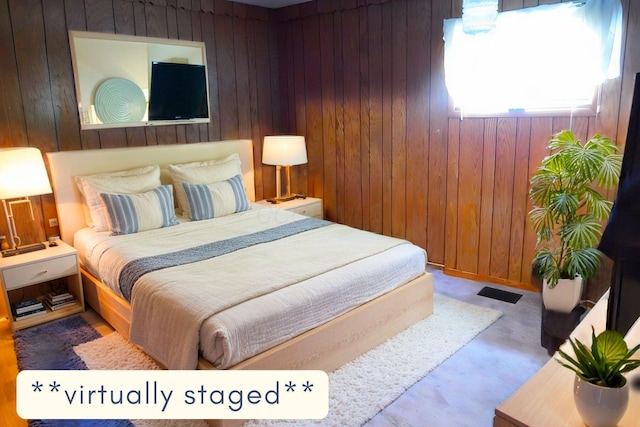 bedroom featuring concrete flooring and wood walls