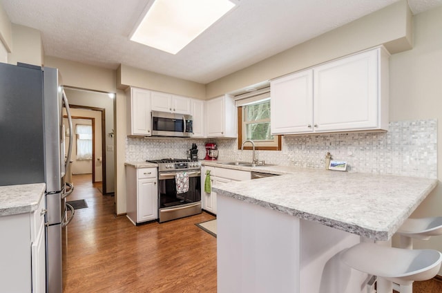 kitchen featuring appliances with stainless steel finishes, sink, white cabinets, and kitchen peninsula